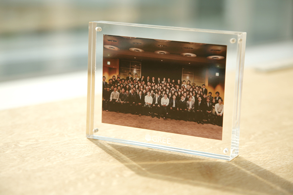 写真上から、グリーの使命がつづられたミッションステートメントカード、今年1月に開かれた納会の記念写真、会社ロゴの入ったマグカップ。これらは会社から社員に送られたノベルティ