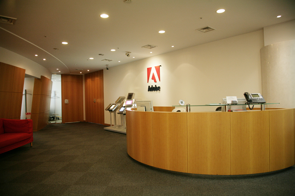 白壁とウッドを基調にデザインされたエントランス。サイドにはアドビを代表するアプリケーションのロゴを映し出したオブジェ