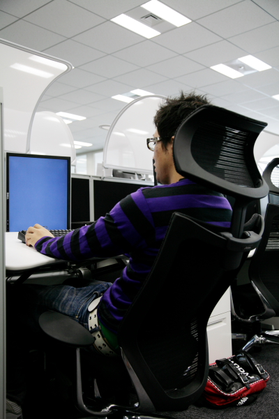 エンジニアが集う執務室の一角。きわめて楽な姿勢でデスクワークに集中できるクルーズ&アトラスのチェアとデスクを配備。グッと背中を傾けて利用するため、天井からの光を遮る白い屋根が各ブースには設置されている