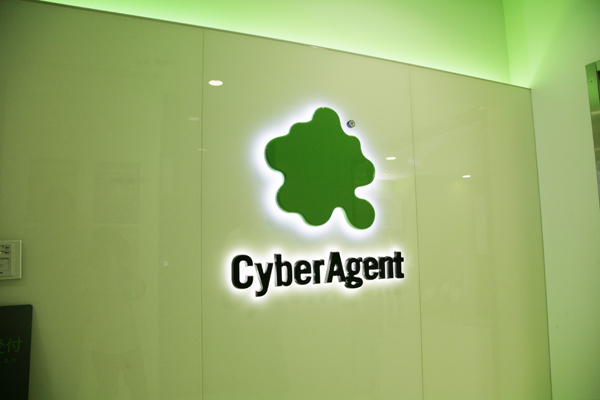 緑のロゴの周囲が白く輝き、周囲の壁は緑に照らされる。アメーバをモチーフとしたCIが印象的に映る