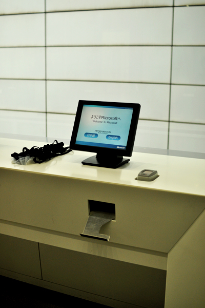 ビルの2階で迎えてくれたのは、日本マイクロソフトがNECと共同開発した、来客管理システム。事前に受けとっていたバーコードをかざすと「待ち合わせ場所」が記された入館証が発行され、訪問先の社員のPCやスマートフォンにもゲストの到着が知らされる