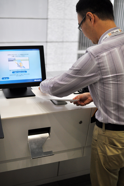 ビルの2階で迎えてくれたのは、日本マイクロソフトがNECと共同開発した、来客管理システム。事前に受けとっていたバーコードをかざすと「待ち合わせ場所」が記された入館証が発行され、訪問先の社員のPCやスマートフォンにもゲストの到着が知らされる