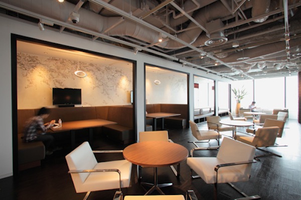 同じくSakura Cafe。エントランスや執務室とは異なり、天井は白。解放感がある。中央部には、沖縄より取り寄せた立派な樹木が、無機質になりがちな空間に潤いを与えている。夜はプロジェクターで、野球中継を映し出すこともあるとか