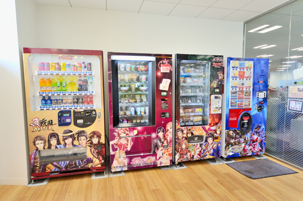 KLabが展開するソーシャルゲームのキャラクターがあしらわれた自動販売機。ソフトドリンクはもちろん、パン、おにぎり、カップ麺などの軽食もある。一番右の自動販売機は、社員にはうれしいフリードリンク