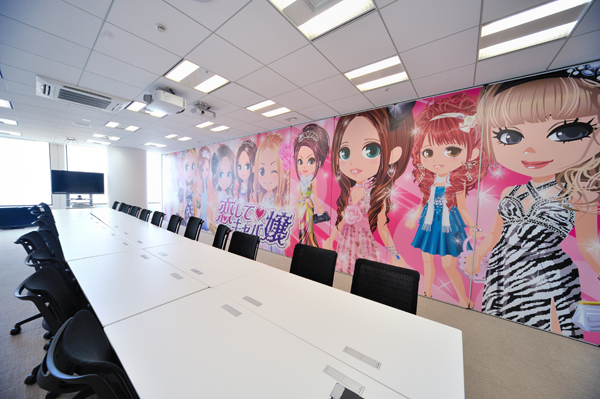 壁一面に「恋するキャバ嬢」のキャラクターがズラリ。この大型のミーティングルームは、24人を収容できる