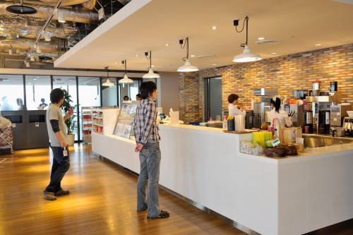 コーヒーの匂いがたちこめる社内カフェ。営業は、9時半から18時半まで。お昼どきにはお弁当も販売。周囲をガラスで囲まれたこの見晴らしのいいスペースを利用して、CMの発表会などが開催されることもある