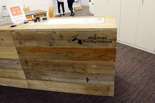 デジタルハリウッド東京本校の学生専用受付。受付カウンターには、ザクッとした質感が楽しい廃材を使用。無機質なオフィスビルの中にあっても、どこか温かみが感じられる