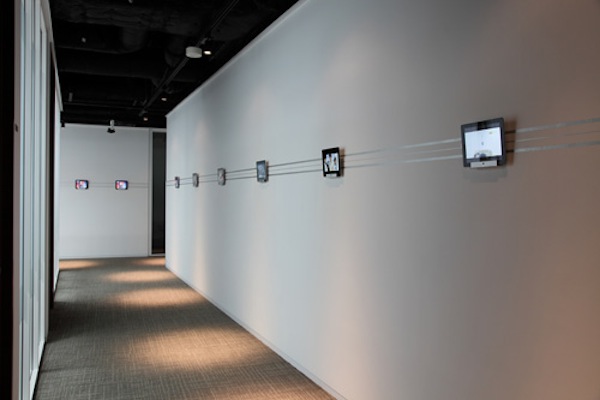 廊下にディスプレイされたiPadには、同社のCMや同社海外ブランチの様子を映し出した映像をエンドレスで放映