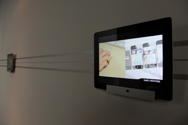 廊下にディスプレイされたiPadには、同社のCMや同社海外ブランチの様子を映し出した映像をエンドレスで放映