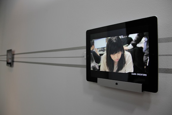 廊下にディスプレイされたiPadには、同社のCMや同社海外ブランチの様子を映し出した映像をエンドレスで放映