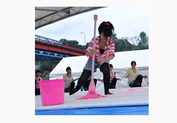 ショッキングピンクのインクを使って大きな筆で文字を書く女子高生