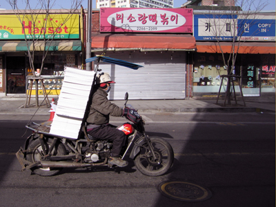 印刷物をはためかせて、ソウルの街中をさっそうと走るバイク！