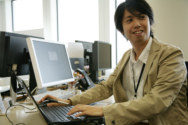 今回お話を聞かせてくださったメディア企画本部の上長、デザイナーの羽根誠さん。左手にウインドウズ、右手にはMacの両刀つかい。取材時はお昼どきだったせいか周囲の人影もまばら