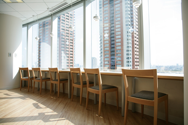 黒と白を基調にデザインされた執務室とは打って変わって、外光がたっぷりと降り注ぐ明るい休憩室。食事中の人々、仕事中の人々など、さまざまな社員がリラックス中