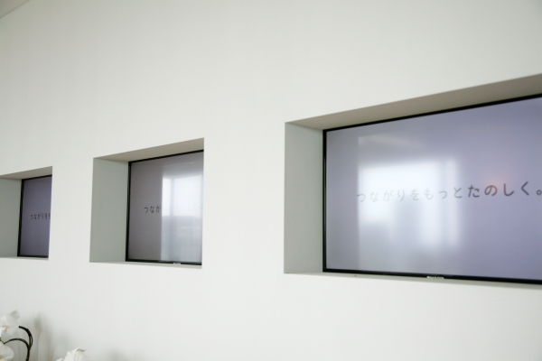 エントランスに設けられた大型スクリーン。mixiのCMなどを映し出す。手前のデスクに用意されたiPadで、映し出すものは選択できる