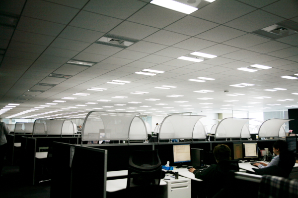 エンジニアが集う執務室の一角。きわめて楽な姿勢でデスクワークに集中できるクルーズ＆アトラスのチェアとデスクを配備。グッと背中を傾けて利用するため、天井からの光を遮る白い屋根が各ブースには設置されている