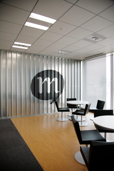 執務室の壁に大きく「m」。mixiのロゴマークのひとつ