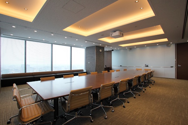 海外の人との打合せに使用するミーティングルーム。ホワイトボードを兼ねたスクリーンに相手の様子が映し出される。部屋の壁に設置されたマジックミラー越しには、通訳ブースも併設。主にエグゼクティブが使用するスペースであるせいか、インテリアはどことなくラグジュアリー