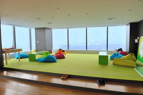 社内カフェを奥へと進むと、グリーンがまぶしいリラックススペース。カラフルなクッションに横たわりながら、おつかれ気味の人たちが休憩中