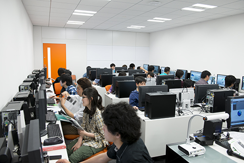 デジタルハリウッド大学、デジタルハリウッド大学院の学生たちが学ぶ3階。白い壁にオレンジのトビラ、メリハリの効いた色彩が心地よい