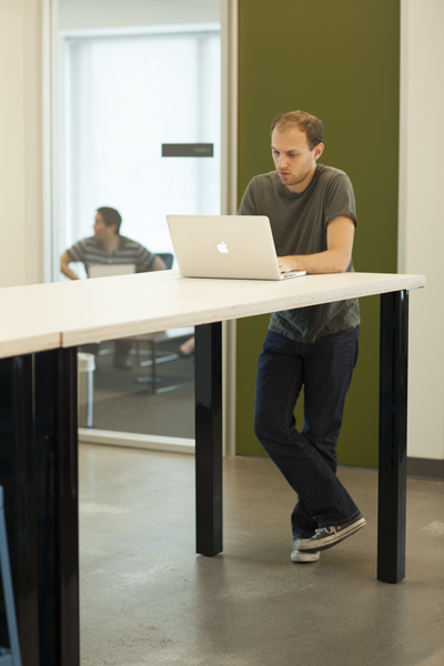 立った姿勢でマシンに向かう人たち。座りっぱなし、運動不足の解消にもいいが、サッとスタッフが集う宿り木のような場所でもある